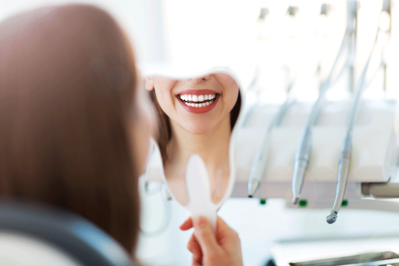 women holding a dental mirror, in dental office, sunshine