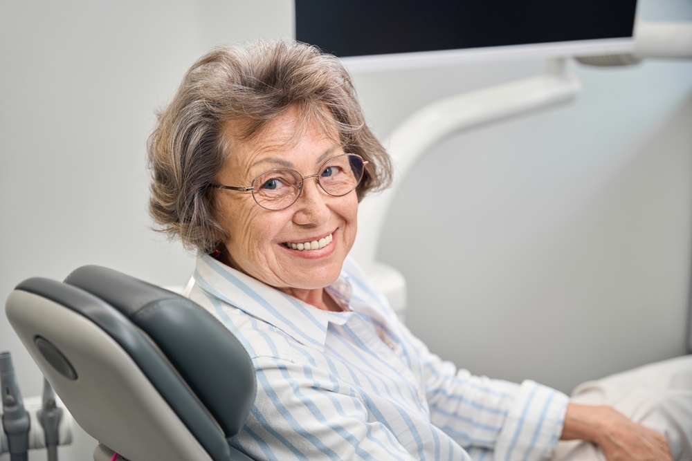 A dentist is carefully examining a patient's dental x-rays, with a tooth implant displayed on the screen. The dentist is explaining the teeth implant procedure to the patient. No text on the image.